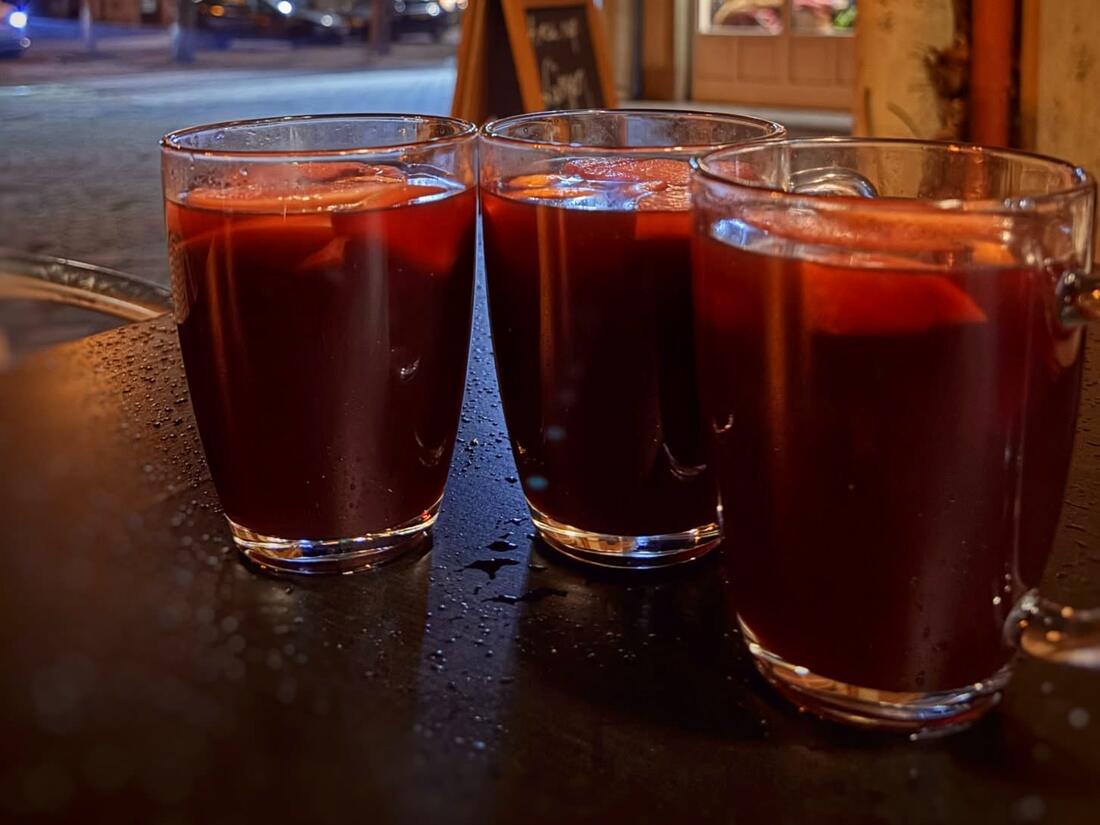 Forralt boros poharak egy teraszasztalon, a háttérben adventi fényekkel